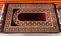 Full view of burgundy velvet prayer rug with gold embroidery and fringe