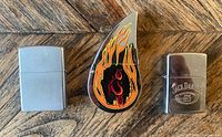 Front view of brushed chrome Zippo, Jack Daniel's Zippo, and flame-shaped Orange County Choppers lighter