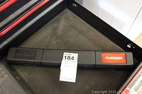 Black hard plastic Husky branded case for torque wrench shown closed and laying in a tool drawer.