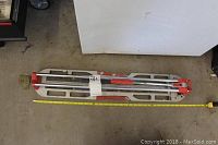 Top view of the 32 inch tile cutter placed on a concrete floor with a measuring tape indicating length.