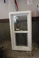 Full view of the white vinyl window with two sash sections and mesh screens, showing overall condition.