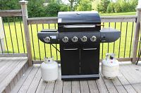 Front view of Masterchef grill with closed lid and two propane tanks