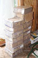 Stacked cardboard boxes of tiles against plywood wall.