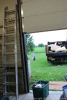 Full view of the 20 foot aluminum extension ladder leaning against a wall near an open garage door with outdoors visible.