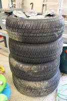 Stack of four mounted tires showing sidewalls and Ford caps on top tire