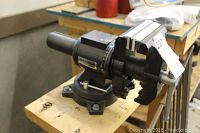 Side view of black cast iron bench vise with silver handle and jaw bumpers mounted on wooden bench