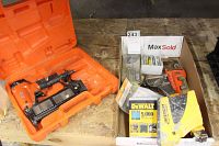 Wide shot showing the orange Air King nail gun in case on the left and two staplers with boxes of staples and nails on the right.