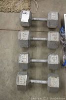Four hex dumbbell weights placed on a concrete floor, showing two 30lb and two 40lb weights arranged in pairs.