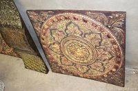Photo showing one square metal wall art panel with ornate embossed circular and floral designs in gold and copper tones.