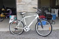 White CCM Noway mountain bike in outdoor setting, gravel ground, with white and black seat and 21-speed gear setup.