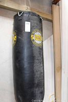 Full view of the black Everlast punching bag hanging, showing length and diameter
