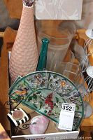 Full view of stained glass cardinal window hanger, pink and teal vases, candle holders and bird figurine grouped on wooden bench