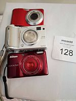 Front view of Fujifilm FinePix E510 atop Nikon Coolpix camera