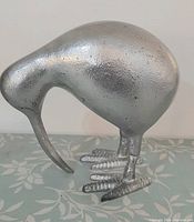 Front-angled view of silver cast metal kiwi bird showing beak, body and feet