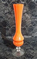 Full view of orange cased glass bud vase showing profile and clear foot