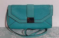 Front view of turquoise snake-embossed leather purse showing overall design and strap