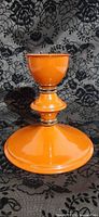 Full view of orange enamel candlestick showing flared base and stem