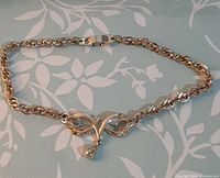 Full view of gold-tone necklace laid flat showing chain and centerpiece