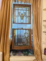 two stained glass panels in natural wood frames hung in window