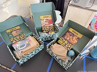 Three open Month's Craft boxes showing contents for birdhouse, whittling and hot sauce kits