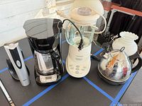 Group shot of four kitchen electrics: coffee maker, blender, wine opener, kettle