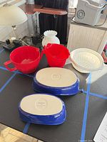 Underside of blue casseroles showing maker’s marks and plastic bowls nearby