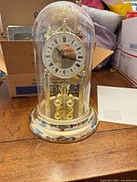 Front view of Kronos anniversary clock under glass dome