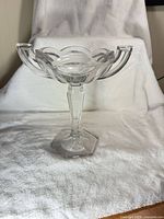 Front view of clear pedestal trophy bowl with handles on white backdrop