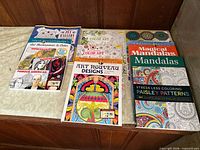 All ten adult coloring books laid out in two rows showing front covers and titles