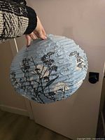 Overall view of folded light blue paper lantern with floral design