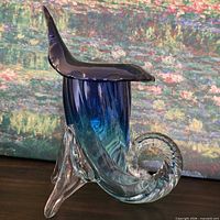 Left side view of cobalt blue to clear glass cornucopia horn on tripod base
