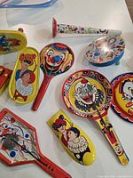 Group of tin litho paddles, horn, clicker
