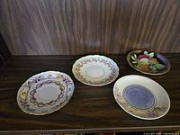 All four dessert plates on shelf showing different patterns