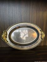Top view of silver-plated oval tray showing rope edge and floral handles