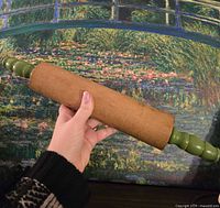 Full view of rolling pin held in hand showing wood barrel and both green handles