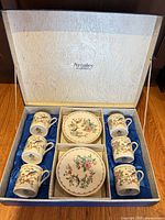Open presentation box showing six cups and six saucers in blue satin lining