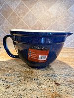 Side view of blue ceramic mixing bowl showing handle, spout and brand sticker