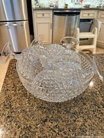 Large clear plastic hobnail punch bowl filled with matching cups, showing texture and transparency