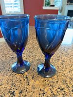 Two cobalt blue pressed glass stemmed goblets on countertop
