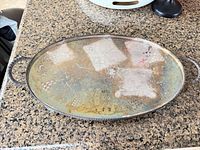 Top view of oval tray showing engravings, tarnish and handles