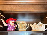 All three decorative ceramic teapots on shelf