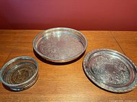 Three silver-plated trays shown together on tabletop