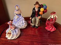 Group shot of four Royal Doulton figurines on wooden surface