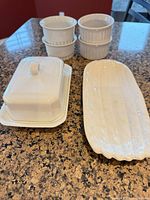 butter dish, platter, four ramekins on countertop