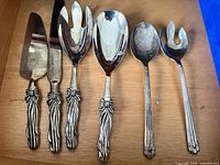 All six silver-tone serving utensils laid out