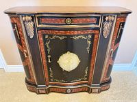 Front view of black lacquer cabinet with faux burl inlay and gilt detailing