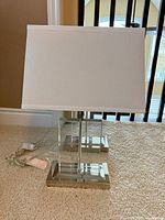 Pair of acrylic table lamps with shades on carpet
