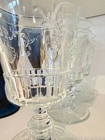 Three clear pressed glass goblets side view