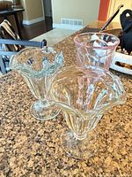 Three footed pressed glass sundae cups in pastel colors on countertop
