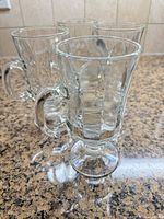 Front angled view of all four clear glass pedestal Irish coffee mugs